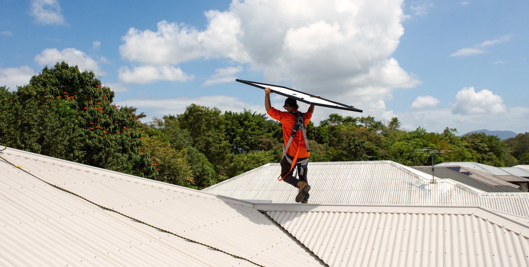 A man holding a solar surfboard on top of a roof, promoting Solar Power.